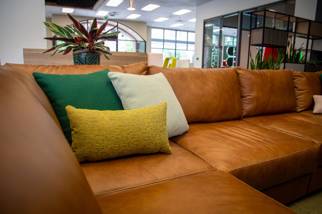 Green, mint, and chartreuse accent pillows on a cognac leather sofa in the Freeform showroom
