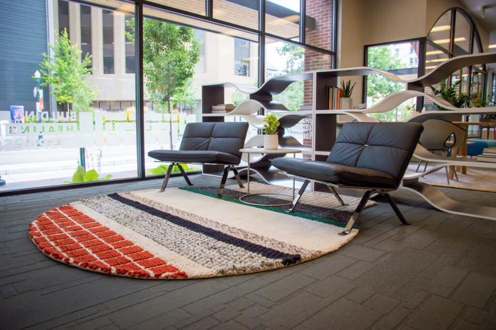 Round striped area rug anchoring two lounge chairs by the showroom windows