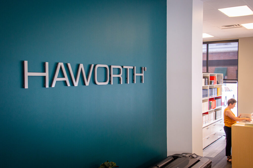 Deep teal painted feature wall with the Haworth logo in the Freeform showroom