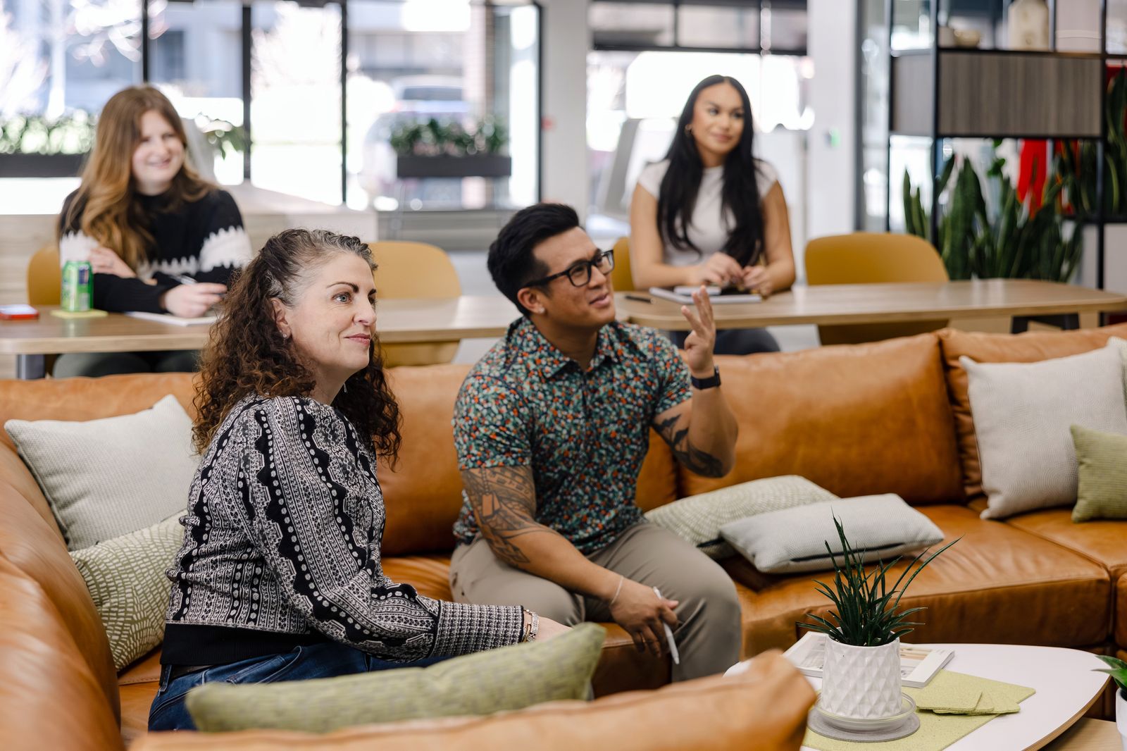 Team members talking on leather sofas in a lounge setting