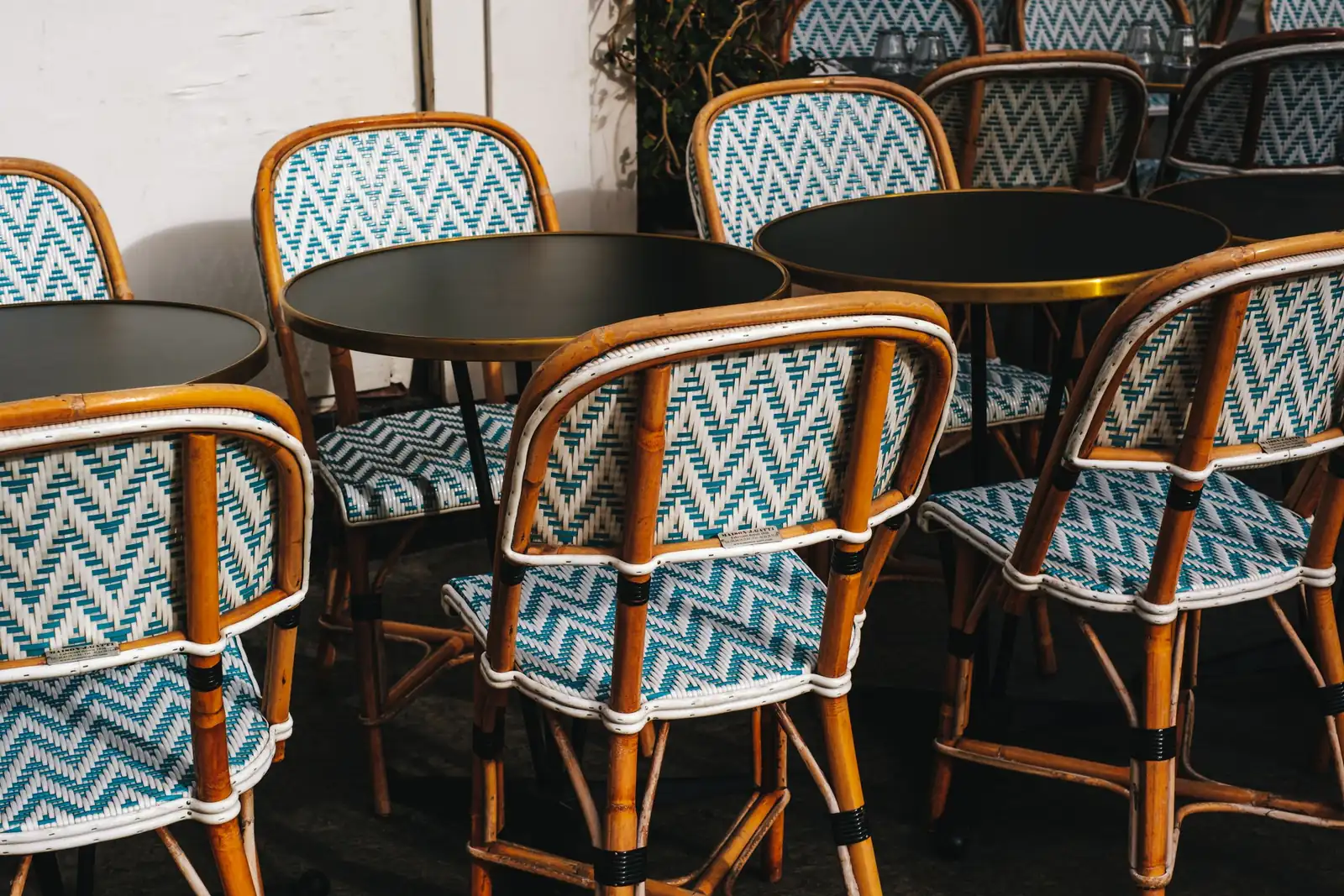 Woven rattan bistro chairs and round cafe tables on a restaurant patio