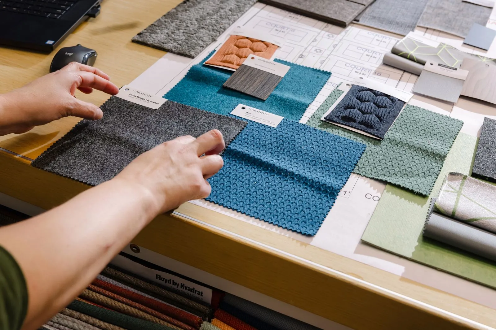 A hand pulling a commercial upholstery sample from a drawer of contract textiles