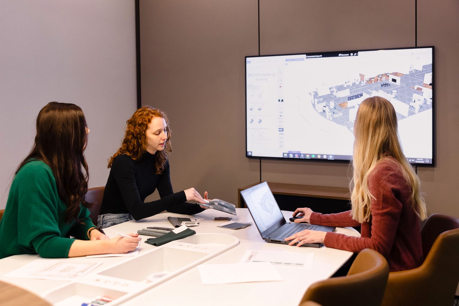 Design team reviewing samples and plans around a meeting table