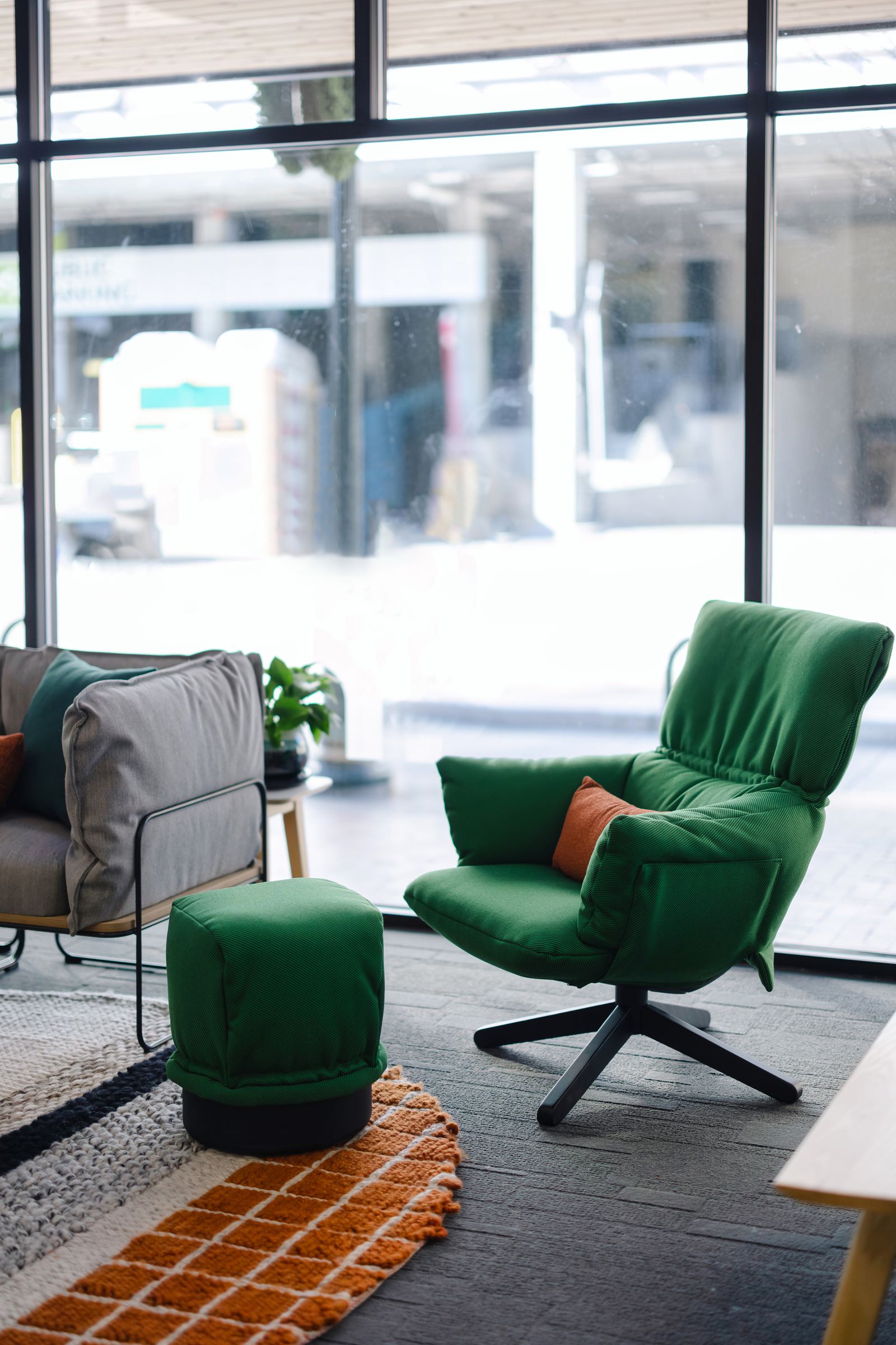 Green wing chair and ottoman beside plants and soft seating