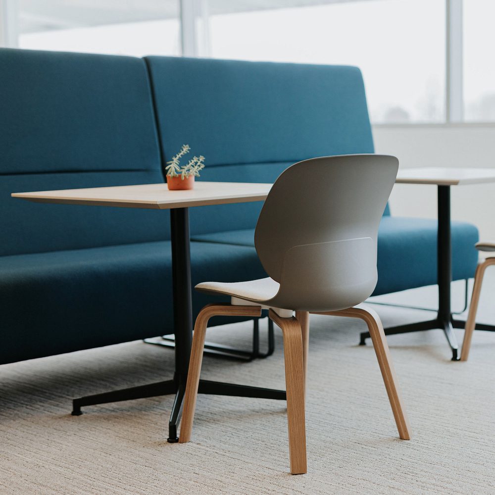 A high-back blue banquette booth with a cafe table and molded wood side chair