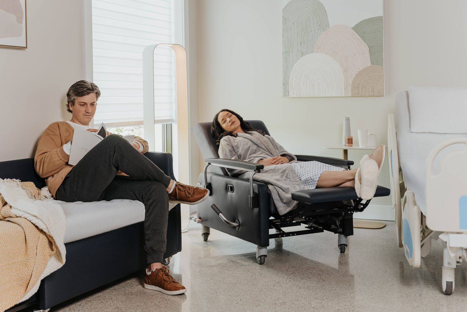 A patient resting in a reclined Haworth Benson chair while a family member visits