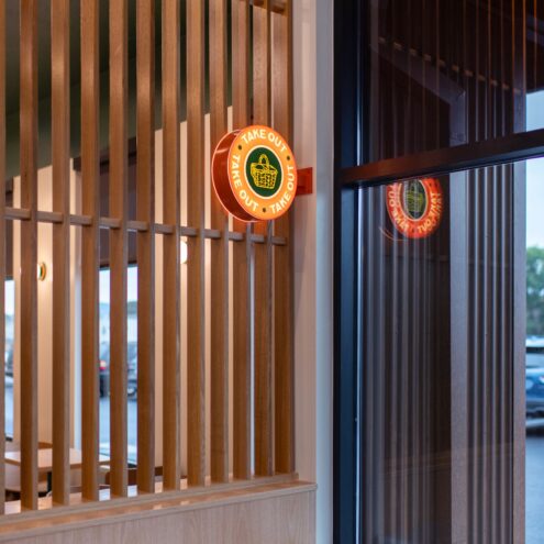 Slatted wood partition and illuminated Kindler's sign by the restaurant entry