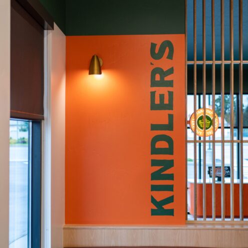 Kindler's orange feature wall with vertical logo, wall sconce and upholstered bench seating