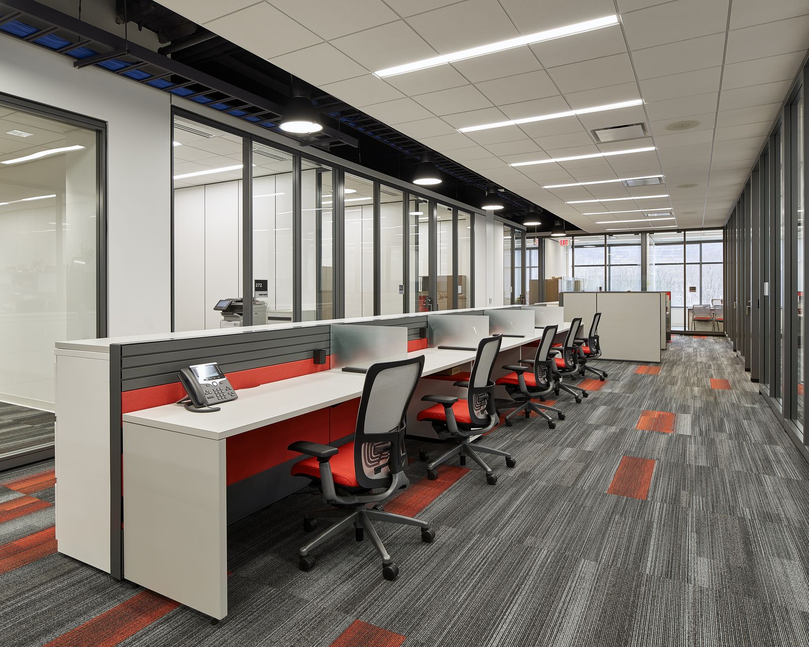 Linear workstation run with red accent panels and mesh task chairs