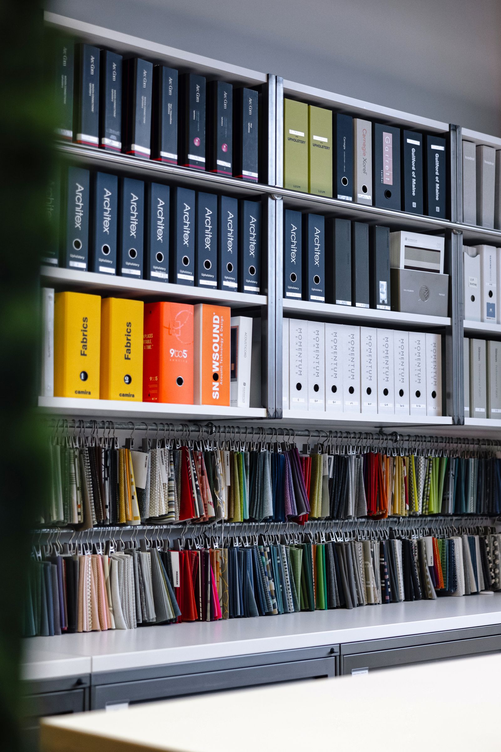 Materials library wall with fabric swatches and finish binders