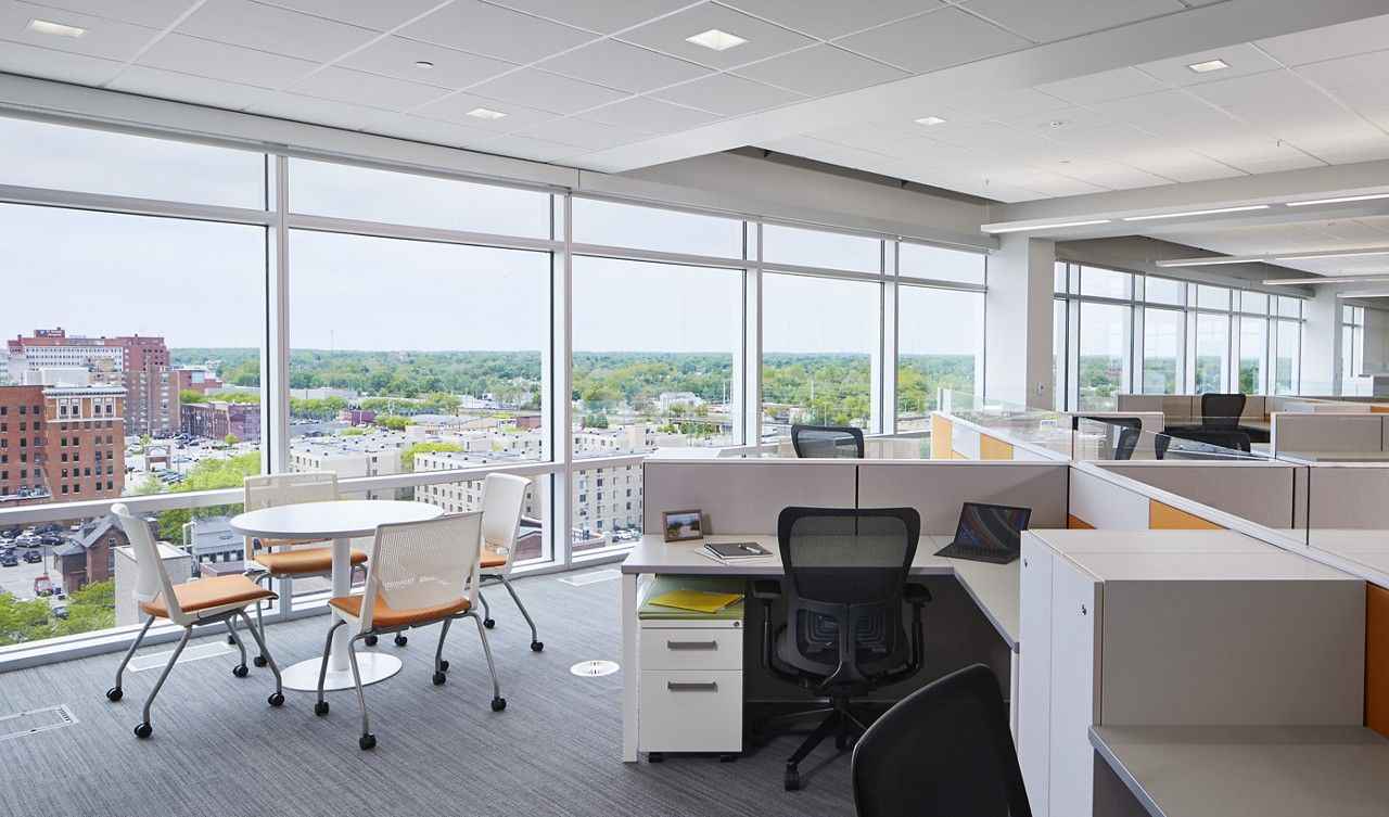 Office workstations and nesting chairs beside floor-to-ceiling windows