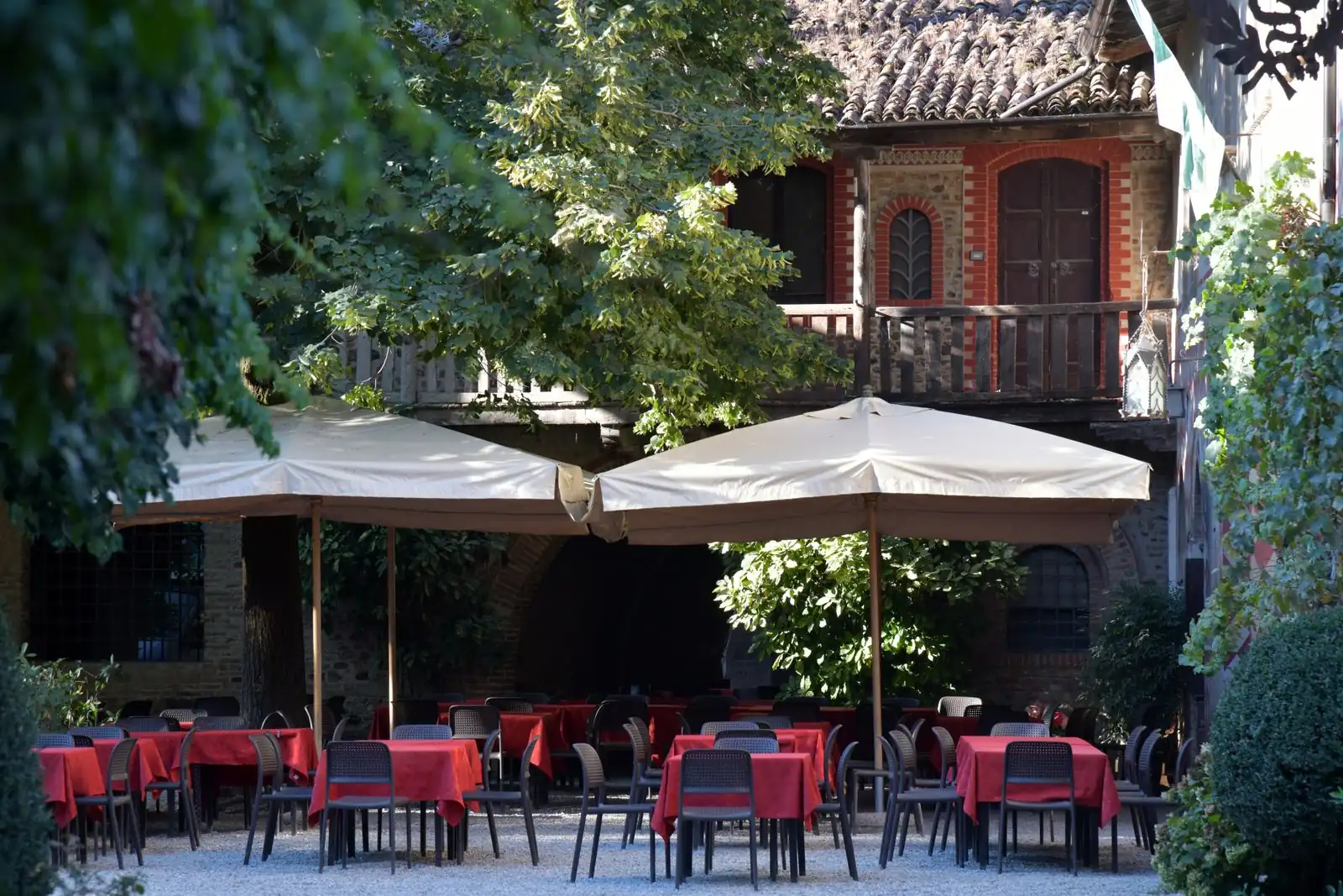 Large cream umbrellas shading outdoor restaurant tables set with red tablecloths