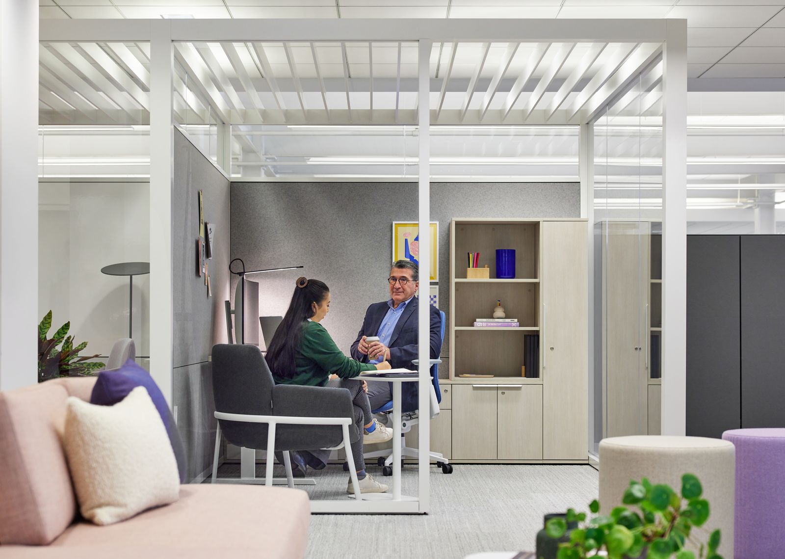 Glass-fronted private office with storage wall and lounge chair