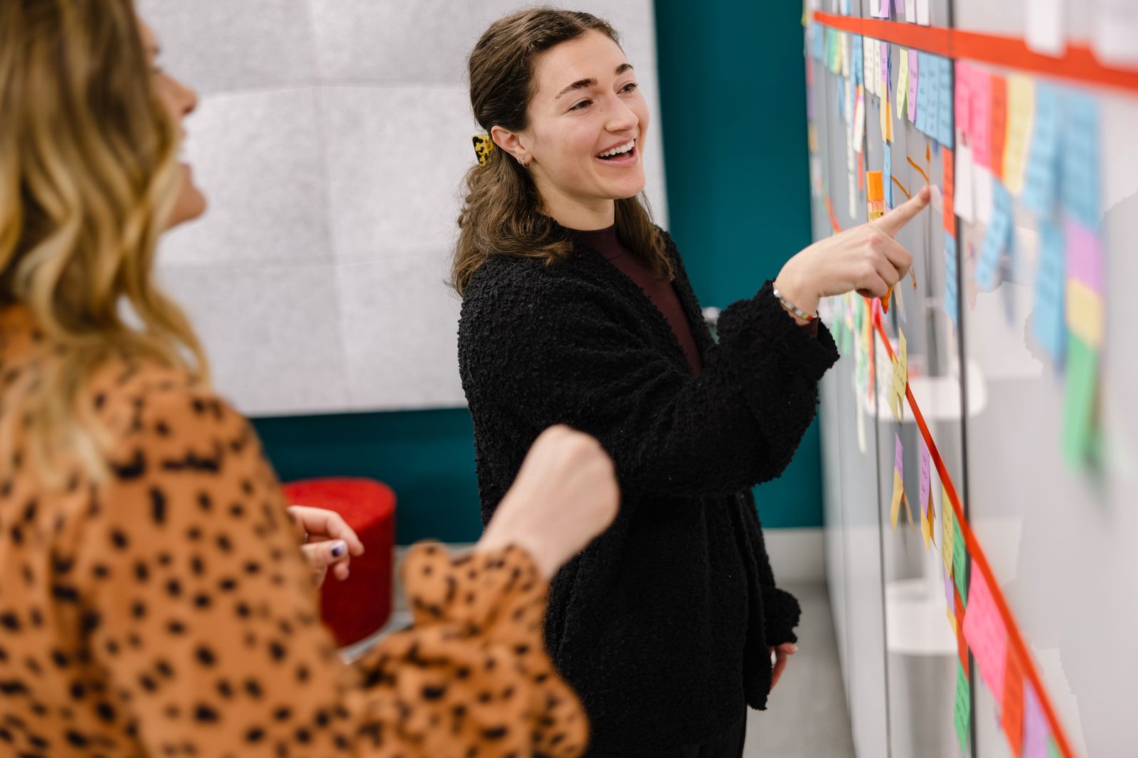 Two colleagues working through sticky notes on a whiteboard